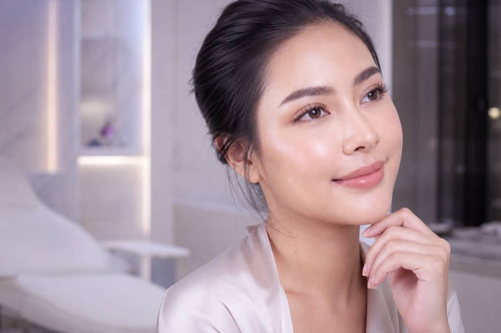 Even-toned editorial skin under soft pearlescent daylight in a private consultation atmosphere