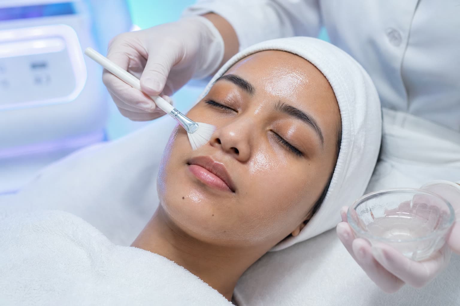 Gloved clinician applying a clear peel solution with a soft fan brush